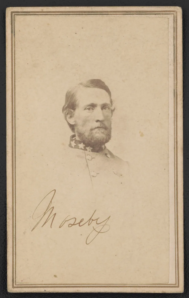 Faded sepia head-and-shoulders portrait on a bordered card: a bearded man in a grey jacket with a dark star-studded collar, with "Mosby" handwritten below.